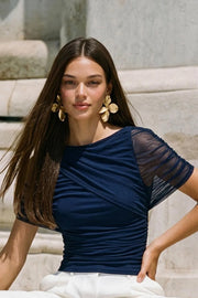 Blusa de mesh, fit ajustado, plisados en costados, cuello barco, detalle decorativo de capas con plisados y manga corta seguidos.