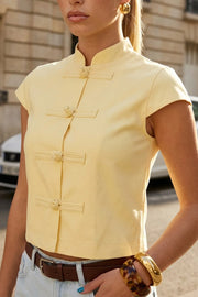 Blusa corta de fit recto, cuello mao, manga corta y cierre frontal con botones alamares.