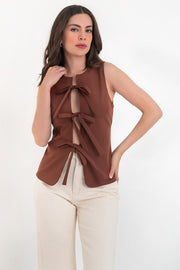 Blusa de fit ajustado, cuello redondo, sin mangas y cierre frontal con lazos amarrables. Detalle de bajo curveado frontal.