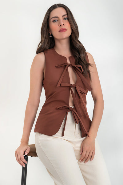 Blusa de fit ajustado, cuello redondo, sin mangas y cierre frontal con lazos amarrables. Detalle de bajo curveado frontal.