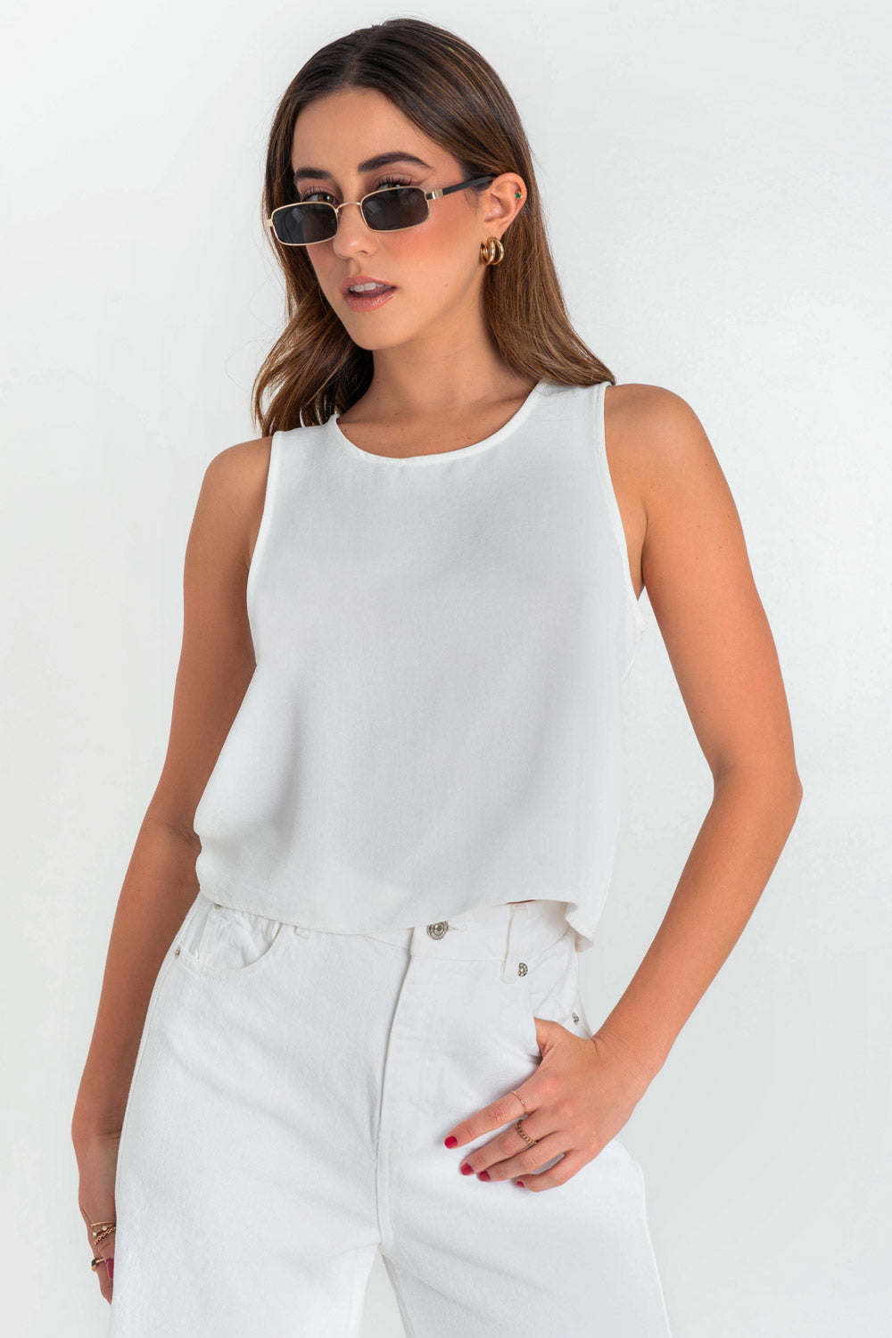 Blusa sin mangas de fit ligeramente oversized, cuello redondo y cierre posterior con botón y ojal.