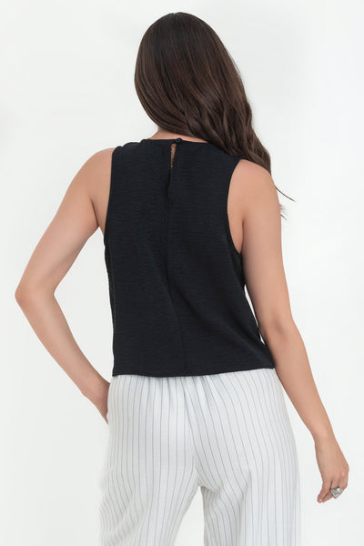Blusa sin mangas de fit ligeramente oversized, cuello redondo y cierre posterior con botón y ojal.