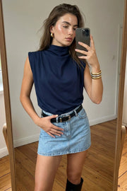 Blusa de fit oversized, sin mangas y cuello alto con detalles plisados en hombros.