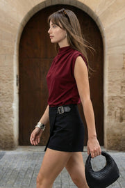 Blusa de fit oversized, sin mangas y cuello alto con detalles plisados en hombros.