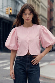 Blusa corta de fit recto, cuello redondo, manga corta amplia globo con volumen en borde, cierre frontal con broches ocultos y bajo curveado frontal.