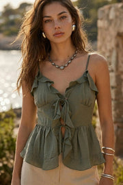 Blusa corta de tirantes delgados ajustables, escote v con olanes en borde, cortes frontales con plisados, peplum con olanes en bajo y cierre frontal con lazos amarrables.