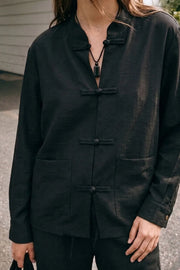 Blusa de manga larga con puño abotonado, fit recto, cuello mao, bolsillos delanteros de parche y cierre frontal con botones alamares.