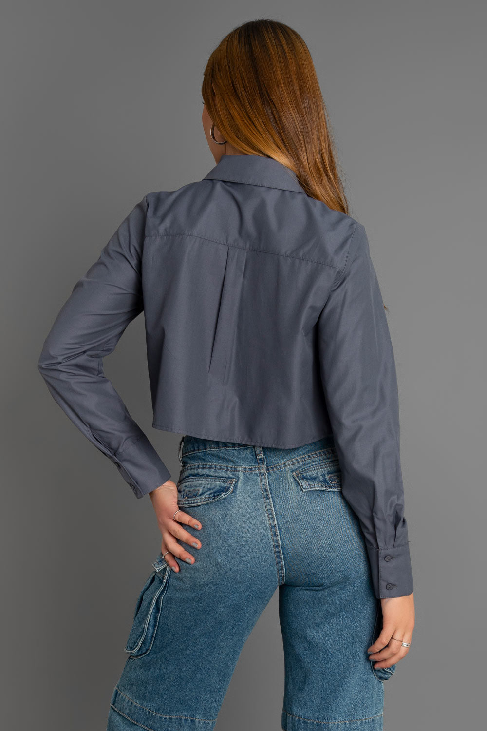 Camisa corta de fit recto, manga larga con puño abotonado, cuello camisero, pinza de amplitud en espalda y cierre frontal con hilera oculta de botones. Detalle de bolsillo frontal con vivo y detalle decorativo en bajo.