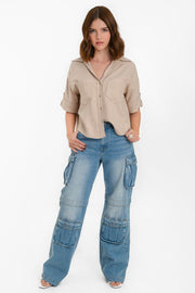 Camisa corta de fit recto, manga corta con doblez en borde y trabillas decorativas laterales, bolsillos frontales de parche, cuello camisero, bajo curveado y pinza de amplitud en espalda. Cierre frontal con hilera de botones en contraste