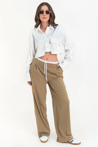 Camisa corta satinada de manga larga con puño abotonado, cuello camisero, fit ligeramente oversized, bolsillos frontales cargo con cartera y cierre frontal con hilera de botones.