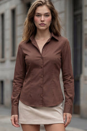 Camisa de fit recto, cuello camisero, manga larga con puño abotonado, pinzas, bajo curveado y cierre frontal con hilera de botones.