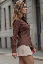 Camisa de fit recto, cuello camisero, manga larga con puño abotonado, pinzas, bajo curveado y cierre frontal con hilera de botones.
