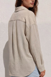 Camisa de fit oversized, cuello camisero, manga larga con puño abotonado, pinza de amplitud en espalda, bolsillo frontal, bajo curveado y cierre frontal con hilera de botones.