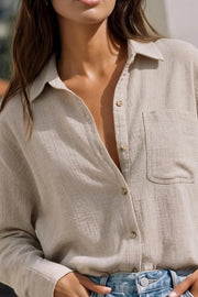 Camisa de fit oversized, cuello camisero, manga larga con puño abotonado, pinza de amplitud en espalda, bolsillo frontal, bajo curveado y cierre frontal con hilera de botones.