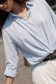 Camisa corta de estampado rayas, fit recto, manga larga rolled up con trabilla ajustable, cuello camisero, cruce frontal con escote v y nudo decorativo en bajo. Detalle de bajo curveado y pinza de amplitud en espalda.