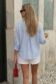 Camisa corta de estampado rayas, fit recto, manga larga rolled up con trabilla ajustable, cuello camisero, cruce frontal con escote v y nudo decorativo en bajo. Detalle de bajo curveado y pinza de amplitud en espalda.