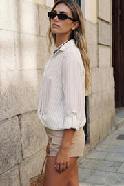 Camisa corta de estampado rayas, fit recto, manga larga rolled up con trabilla ajustable, cuello camisero, cruce frontal con escote v y nudo decorativo en bajo. Detalle de bajo curveado y pinza de amplitud en espalda.