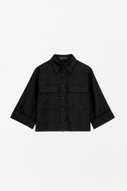 Camisa corta de estilo utilitario. Corte recto, silueta amplia y largo crop. Frente con cuello camisero clásico, tapeta de botones y dos bolsillos con tapa en el pecho. Espalda con canesú y tablón central invertido.