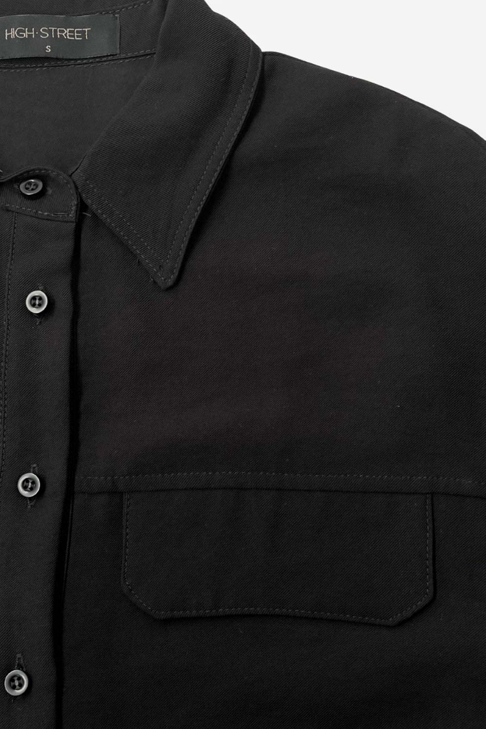 Camisa corta de estilo utilitario. Corte recto, silueta amplia y largo crop. Frente con cuello camisero clásico, tapeta de botones y dos bolsillos con tapa en el pecho. Espalda con canesú y tablón central invertido.