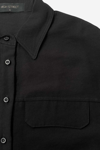 Camisa corta de estilo utilitario. Corte recto, silueta amplia y largo crop. Frente con cuello camisero clásico, tapeta de botones y dos bolsillos con tapa en el pecho. Espalda con canesú y tablón central invertido.