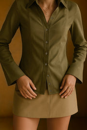Camisa de fit ajustado, cuello camisero, manga larga amplia con botones, pinzas, bajo curveado y cierre frontal con hilera de botones.