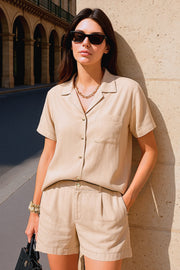 Camisa corta de lino, fit recto, manga corta, cuello camisero, bolsillo frontal de parche, bajo curveado con aberturas laterales y cierre frontal con hilera de botones.