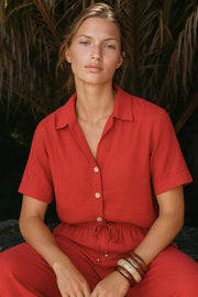 Camisa corta de fluido, manga corta de hombro caído, fruncido decorativo posterior con plisados, cuello camisero, escote v y cierre frontal con hilera de botones en contraste.