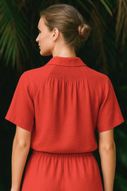 Camisa corta de fluido, manga corta de hombro caído, fruncido decorativo posterior con plisados, cuello camisero, escote v y cierre frontal con hilera de botones en contraste.
