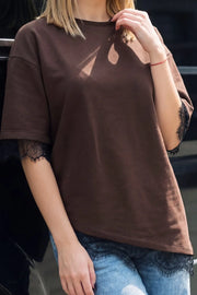 Camiseta básica de fit oversized, cuello redondo, manga corta y bajo asimétrico con encaje decorativo en borde.