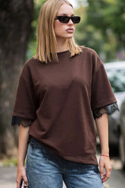 Camiseta básica de fit oversized, cuello redondo, manga corta y bajo asimétrico con encaje decorativo en borde.