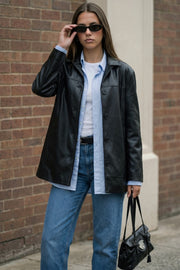 Blazer de efecto piel, fit ligeramente oversized, con solapa y hombreras, manga larga con puño abotonado, costuras decorativas y bolsillos delanteros con vivos. Detalle de abertura posterior en bajo y cierre frontal con hilera de botones.
