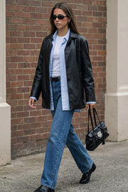 Blazer de efecto piel, fit ligeramente oversized, con solapa y hombreras, manga larga con puño abotonado, costuras decorativas y bolsillos delanteros con vivos. Detalle de abertura posterior en bajo y cierre frontal con hilera de botones.