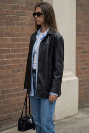 Blazer de efecto piel, fit ligeramente oversized, con solapa y hombreras, manga larga con puño abotonado, costuras decorativas y bolsillos delanteros con vivos. Detalle de abertura posterior en bajo y cierre frontal con hilera de botones.