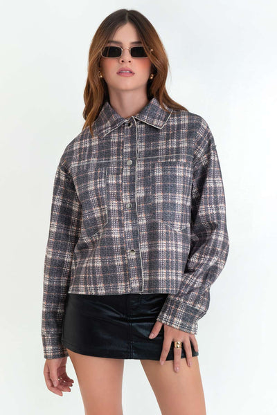 Chamarra corta de fit ligeramente oversized, estampado check, cuello camisero, manga larga con puño abotonado, bolsillos frontales de parche y cierre frontal con hilera de botones en contraste.