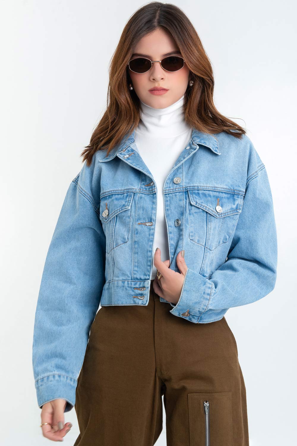 Chamarra corta de denim, fit ligeramente oversized, manga larga con puño abotonado, cuello clásico, bolsillos frontales con cartera y botón en contraste. Cierre frontal con hilera de botones en contraste.
