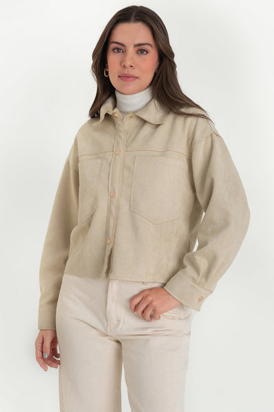 Chamarra corta de gamuza, fit oversized, cuello camisero, manga larga con puño abotonado, corte de bata frontal y posterior, bolsillos frontales de parche y cierre frontal con hilera de botones en contraste.