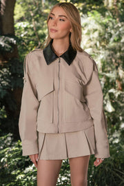 Chamarra de fit oversized, manga larga amplia con puño abotonado, trabillas decorativas con botón en hombros, bolsillos delanteros xl de parche con cartera y cierre frontal con cremallera visible en contraste. Detalle de cuello en contraste.