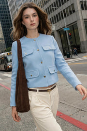 Chamarra corta de fit recto, manga larga, cuello redondo, bolsillos decorativos con cartera y botones en contraste. Cierre frontal con hilera de botones de presión.