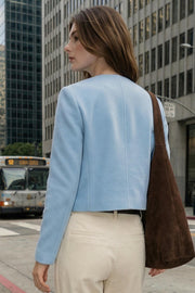 Chamarra corta de fit recto, manga larga, cuello redondo, bolsillos decorativos con cartera y botones en contraste. Cierre frontal con hilera de botones de presión.