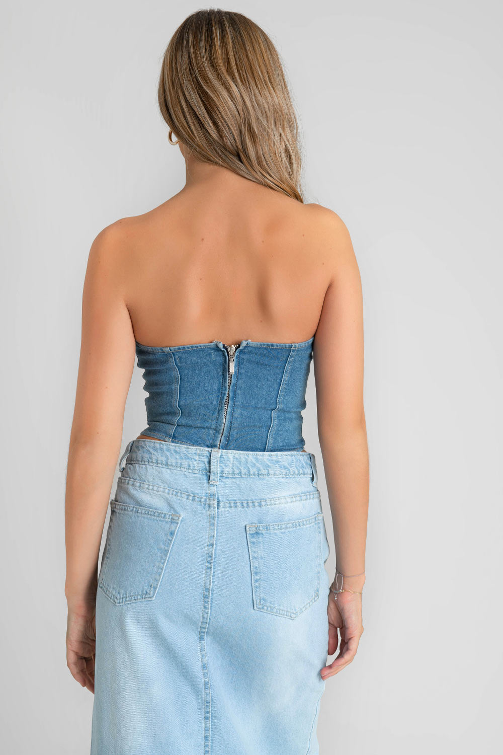 Corset de denim en lavado medio, escote corazón, fit ajustado, costuras decorativas frontales y cierre posterior con cremallera visible en contraste