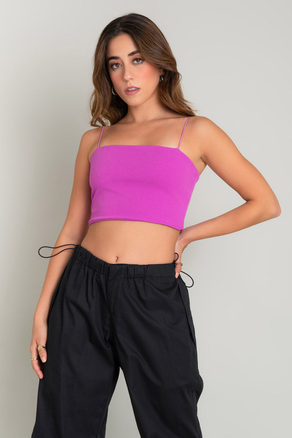 Crop top bandeau de fit ajustado, escote recto y tirantes delgados elásticos. Cierre posterior con cremallera visible.