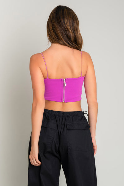 Crop top bandeau de fit ajustado, escote recto y tirantes delgados elásticos. Cierre posterior con cremallera visible.