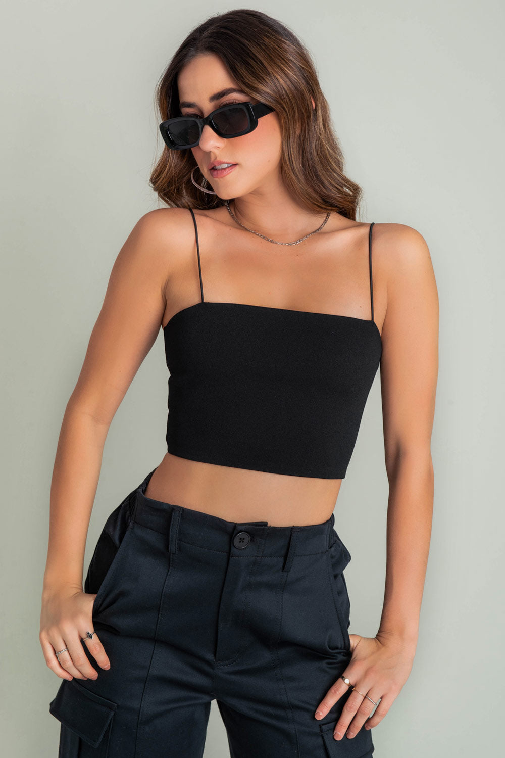 Crop top bandeau de fit ajustado, escote recto y tirantes delgados elásticos. Cierre posterior con cremallera visible.