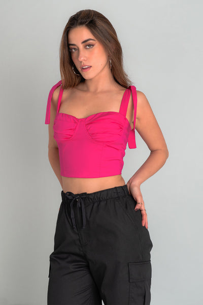 Crop top de fit ajustado, escote corazón con cortes decorativos y detalles plisados, costuras frontales y tirantes con nudo amarrable. Fruncido en espalda y cierre posterior con cremallera visible en contraste.