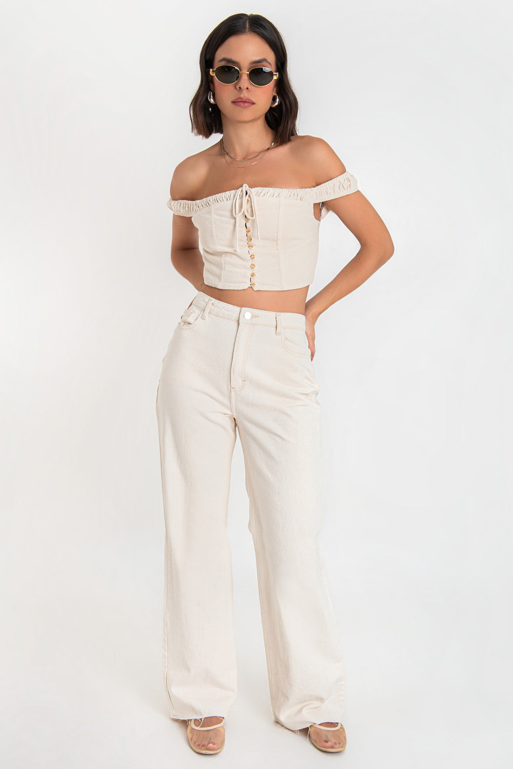 Crop top de lino, fit ajustado, hombros descubiertos, escote con plisados decorativos en borde y jareta frontal ajustable, tirantes plisados, costuras decorativas frontales y cierre posterior con cremallera visible en contraste.