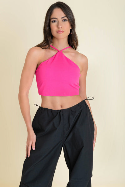 Crop top de cuello halter con tirantes delgados ajustables, fit ajustado y cierre posterior con cremallera visible en contraste.