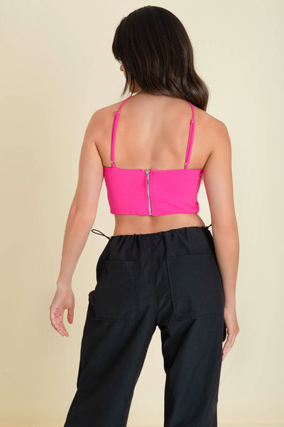 Crop top de cuello halter con tirantes delgados ajustables, fit ajustado y cierre posterior con cremallera visible en contraste.