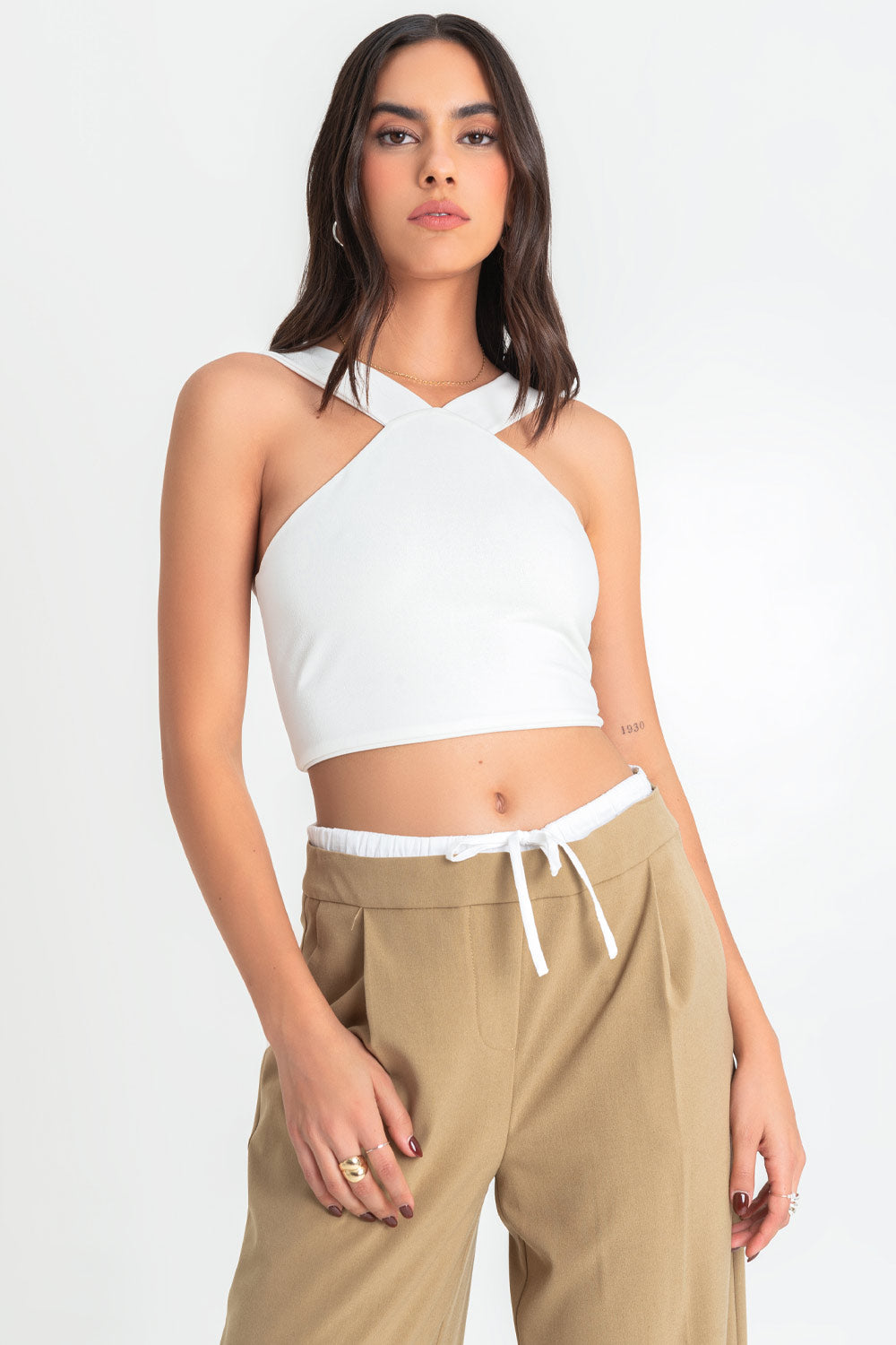 Crop top de cuello halter v con tirantes, fit ajustado y cierre posterior con cremallera visible en contraste.