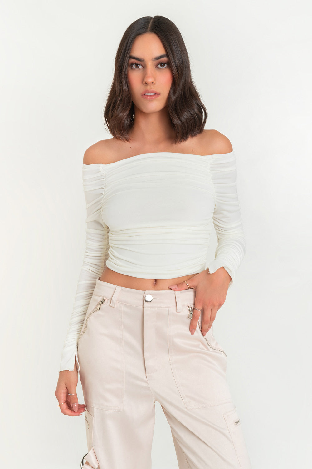 Crop top de fit ajustado, plisados en costados, hombros desubiertos, escote recto con plisados y manga larga plisada con abertura en puño. 