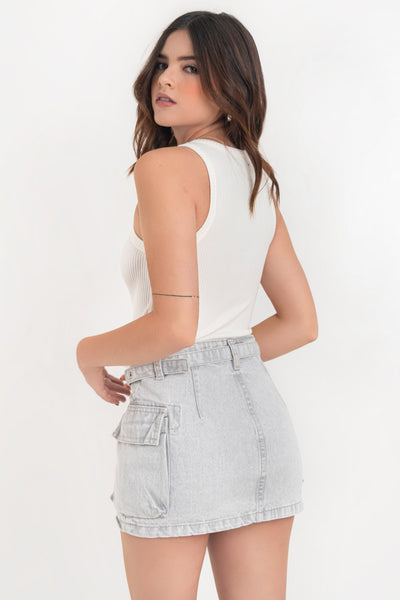 Falda corta cargo de denim, fit ajustado, cintura alta con pretina y trabillas, bolsillos laterales cargo con cartera y cinturón con hebilla en contraste. Cierre frontal con cremallera oculta y botón en contraste.